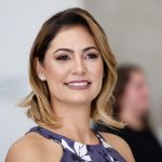 Retrato oficial de Michelle Bolsonaro, ex-primeira-dama brasileira, sorrindo em cerimônia pública.