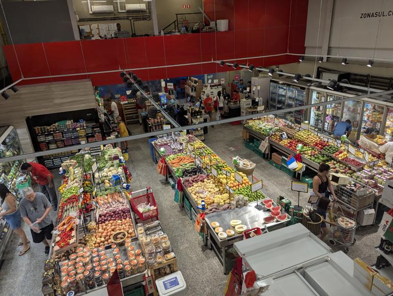 Interior do supermercado Zona Sul de Laranjeiras no Rio de Janeiro demonstrando a oferta de alimentos e a movimentação do comércio.