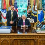 O senador brasileiro Flávio Bolsonaro em pé ao lado do ex-presidente norte-americano Donald Trump no Salão Oval da Casa Branca.