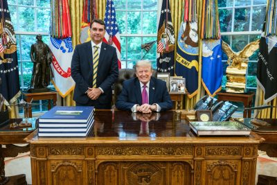 O senador brasileiro Flávio Bolsonaro em pé ao lado do ex-presidente norte-americano Donald Trump no Salão Oval da Casa Branca.