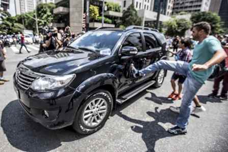 O carro que transportava o secretário de segurança pública, Alexandre de Moraes, sendo chutado por manifestante. Foto: Felipe Larozza/VICE