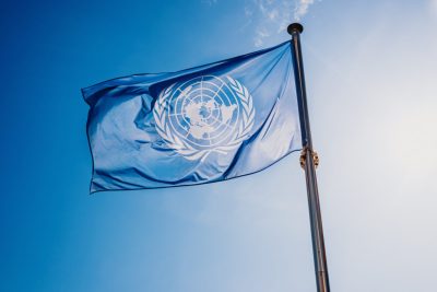 ONU, Nações Unidas, bandeira, relações internacionais, paz, símbolo global, diplomacia, céu azul, cooperação, organização mundial.