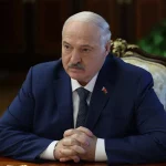 Presidente Alexander Lukashenko em reunião oficial, com bandeira da Bielorrússia no paletó. (Foto: rt.com)
