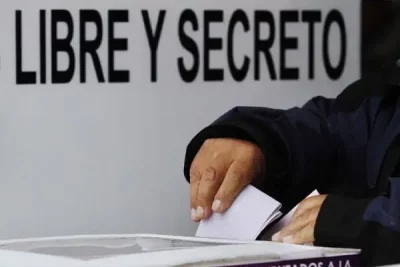 Um eleitor deposita voto em urna com placa "LIBRE Y SECRETO" ao fundo. (Foto: regeneracion.mx)