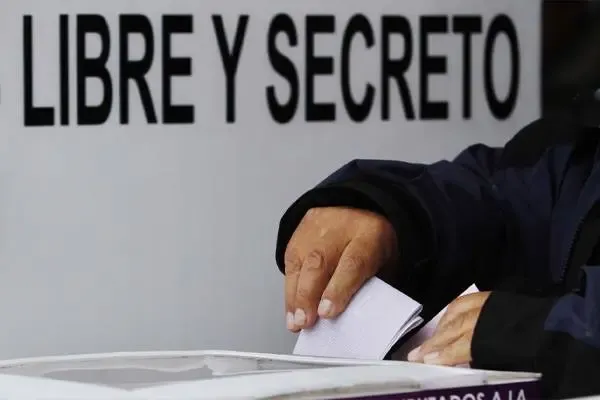 Um eleitor deposita voto em urna com placa "LIBRE Y SECRETO" ao fundo. (Foto: regeneracion.mx)
