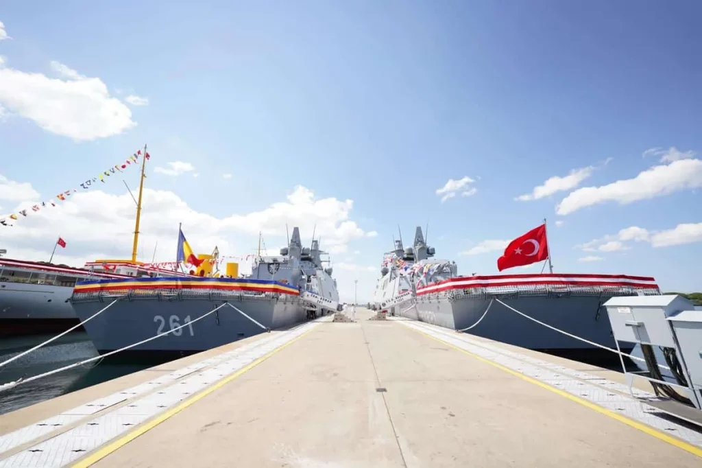 Navios TCG Koçhisar e CAm. Roman atracados em cerimônia de entrega, com bandeiras turca e romena hasteadas. (Foto: navalnews.