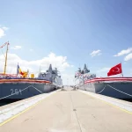 Navios TCG Koçhisar e CAm. Roman atracados em cerimônia de entrega, com bandeiras turca e romena hasteadas. (Foto: navalnews.
