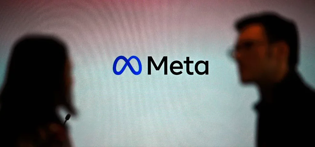 Logo da Meta em exposição, com pessoas ao fundo. (Foto: techcrunch.com)