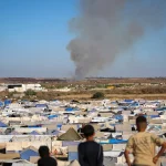 Crianças observam colunas de fumaça em campo de refugiados em Gaza. (Foto: aljazeera.com)