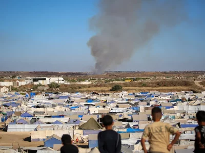 Crianças observam colunas de fumaça em campo de refugiados em Gaza. (Foto: aljazeera.com)