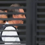 O ex-presidente Jair Bolsonaro é visto em trânsito, acompanhado por um agente da Polícia Militar. (Foto: g1.globo.com)