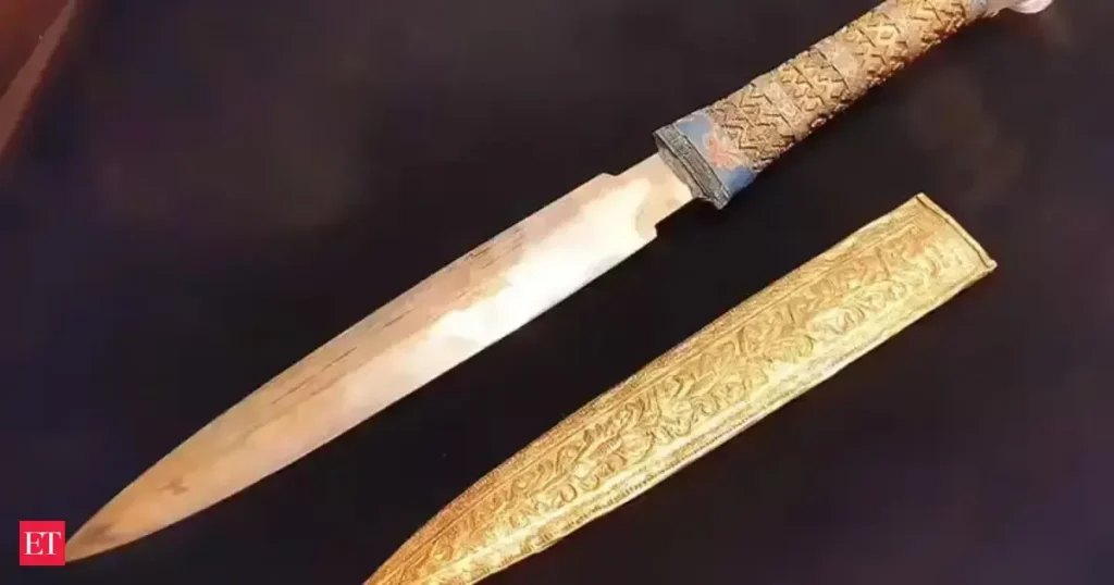 Antiga adaga com cabo ornamentado e bainha dourada, objeto de estudo arqueológico. (Foto: economictimes.indiatimes.com)