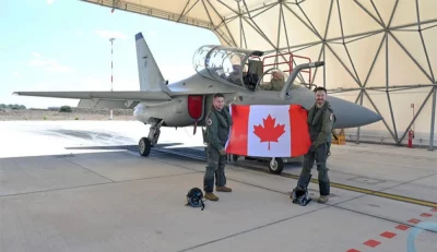 Pilotos da RCAF posam com a bandeira canadense ao lado de um avião na Base da Força Aérea Italiana Decimomannu. (Foto: defesa