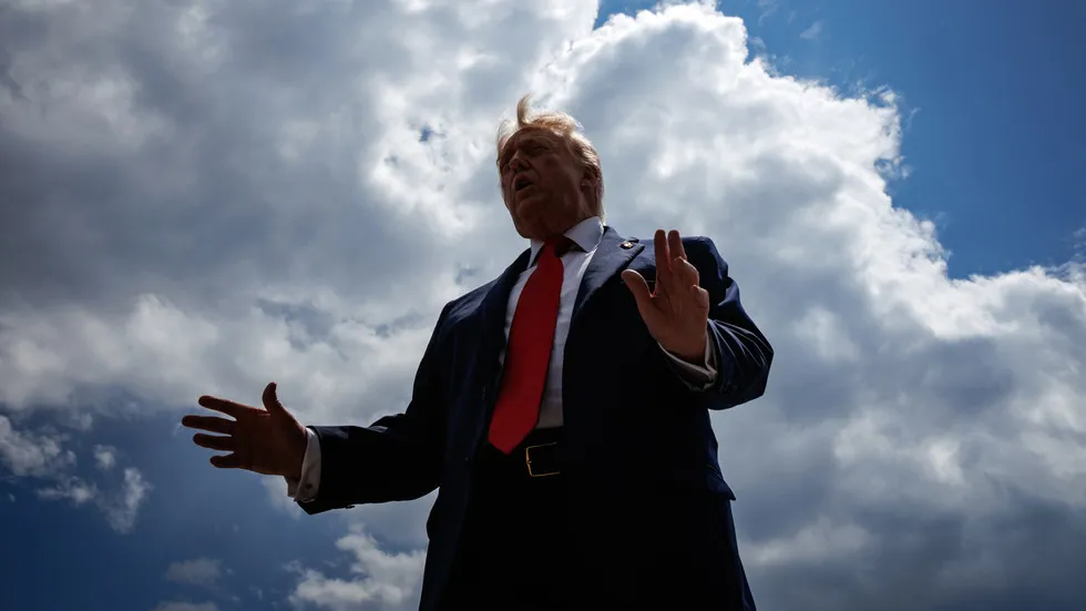 O ex-presidente Donald Trump discursa ao ar livre com gestos abertos, contra um céu nublado. (Foto: rt.com)