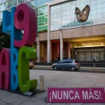 Escultura com as letras "49 ABC" e placa que diz "¡NUNCA MÁS!" em frente a edifício, em referência ao caso Guardería ABC. (Fo