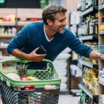 Homem escolhe produto em supermercado com carrinho de compras. (Foto: DECO.PROTESTE.PT)