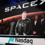 Elon Musk discursa em evento da SpaceX, com imagem de equipe ao fundo. (Foto: techcrunch.com)