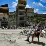 Homem observa a destruição de edifícios em meio a escombros no sul do Líbano. (Foto: aljazeera.com)
