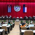 Parlamentares cubanos votam em sessão com bandeiras nacionais ao fundo. (Foto: telesurtv.net)