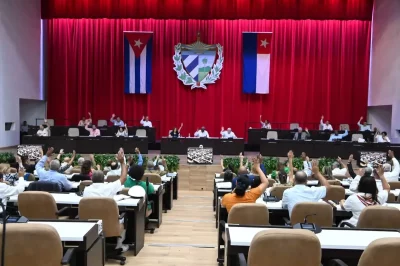 Parlamentares cubanos votam em sessão com bandeiras nacionais ao fundo. (Foto: telesurtv.net)