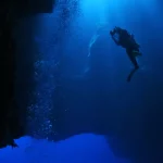 Um mergulhador explora as profundezas da Fossa das Marianas, iluminado por raios de luz subaquática. (Foto: spacedaily.com)
