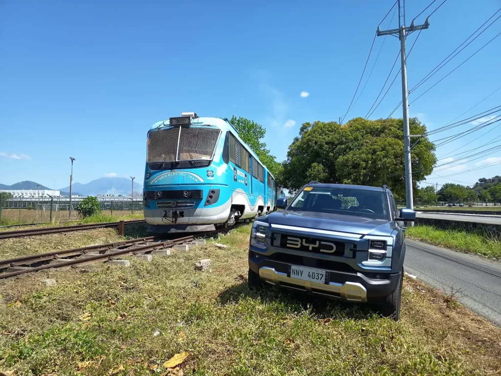 Um veículo elétrico híbrido da BYD e um trem híbrido estão estacionados lado a lado em uma área ao ar livre. (Foto: cleantech