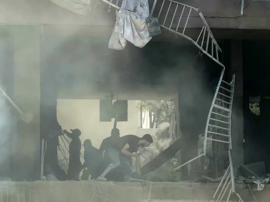 Pessoas em meio aos escombros de um prédio danificado por ataque, em Beirute. (Foto: aljazeera.com)