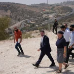 Um grupo de pessoas caminha por área com vista para estradas e colinas em território palestino. (Foto: aljazeera.com)