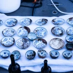 Várias peças de porcelana chinesa com desenhos azuis e brancos são exibidas sobre tecido branco, possivelmente após recuperaç