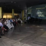 Um homem discursa em evento comemorativo da Agencia Prensa Latina, com público atento e telão ao fundo. (Foto: telesurtv.net)