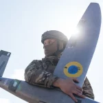 Soldado segura drone militar sob sol brilhante. (Foto: rt.com)