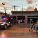 Veículo da Polícia Civil do Acre em frente a edifício com grupo de pessoas observando, em área residencial. (Foto: g1.globo.c